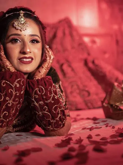 A close-up bridal portrait with dramatic red lighting, focusing on her expressive eyes and beautiful smile.