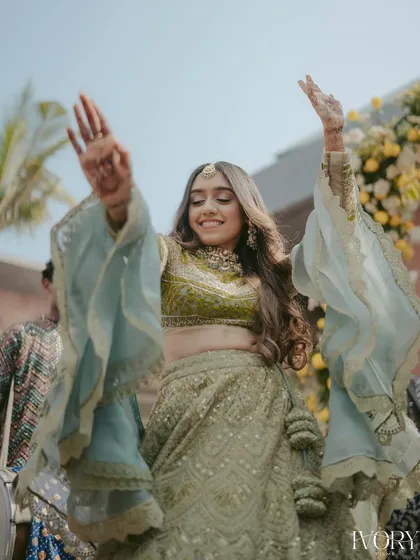 The bride's joyful dance as she enters her Mehendi ceremony. Her flowing sleeves and happy expression create a beautiful sense of movement and celebration.