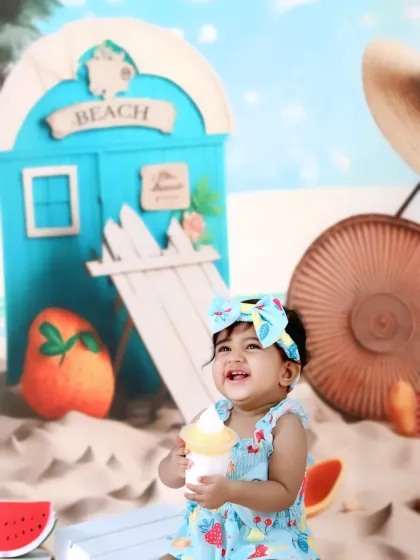 A baby girl laughs with delight while holding a toy ice cream cone during her fun-filled beach-themed photoshoot.