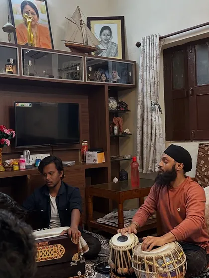 A wider view of the intimate baithak setting, performing for Pt. Mukund Bhale ji. The portraits of legendary musicians in the background add to the traditional atmosphere.