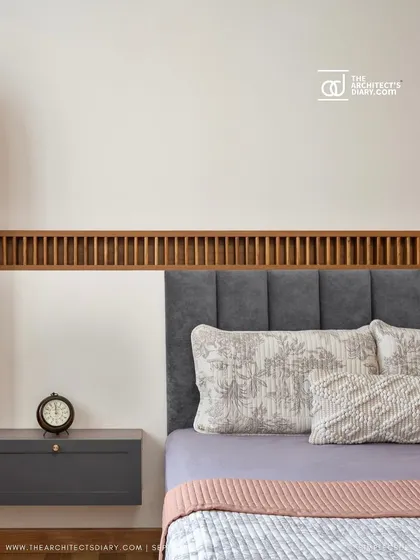 The guest bedroom in 'Cover me in Sunshine' features a custom bed with a grey upholstered headboard and an integrated arched puja unit.