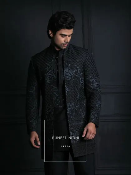 I designed this midnight-black achkan for the man who appreciates understated elegance. The slim, knee-length silhouette features a unique lattice texture and subtle ink-blue ornamental embroidery, creating a modern yet powerful statement for any evening affair.