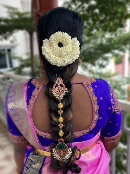 This bridal braid features a modern twist with decorative hair accessories woven into the braid, along with a traditional jasmine flower arrangement at the top.