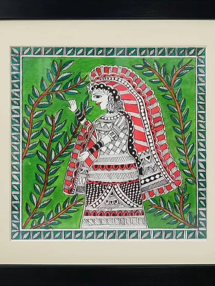 A woman dressed in intricately patterned traditional clothing stands amidst lush greenery in this Madhubani painting by Anu Bansal. The detailed line work on her attire is a highlight of the piece.