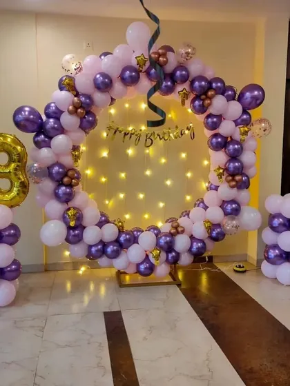 A purple and pink balloon ring for a 13th birthday, with fairy lights creating a starry background.