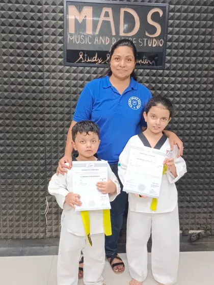 Two young brothers celebrate their taekwondo achievement together, both earning their yellow belts. It's wonderful to see siblings supporting each other on their learning journey.