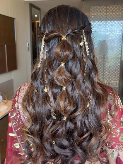 A modern and chic take on a half-up style, featuring a bubble braid adorned with intricate gold charms. This is a great option for a Sangeet or Mehendi, offering a unique and highly photogenic look.