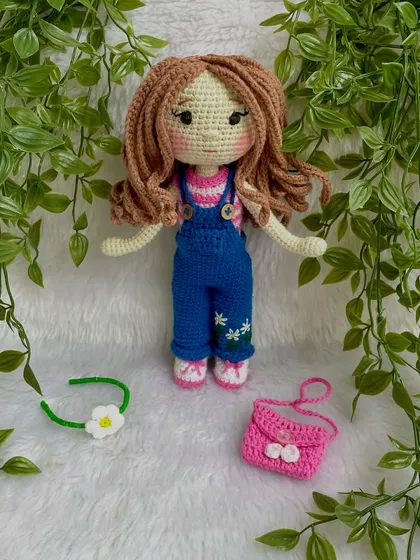 A closer look at the doll in her first outfit. The details on the overalls, like the little embroidered daisies, make her extra special. The clothes are designed to be easy for children to put on and take off.