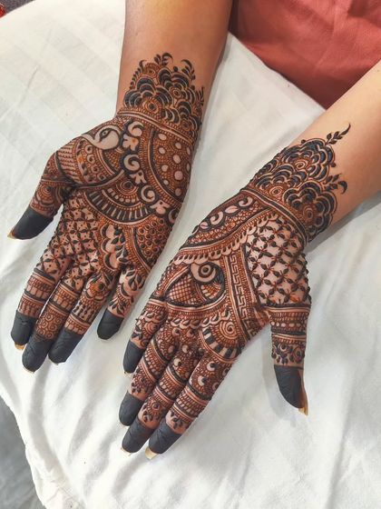 This traditional mehendi for Teej is dense with intricate patterns. It includes a peacock motif, checkerboard fills, and detailed finger designs, resulting in a rich and classic look.