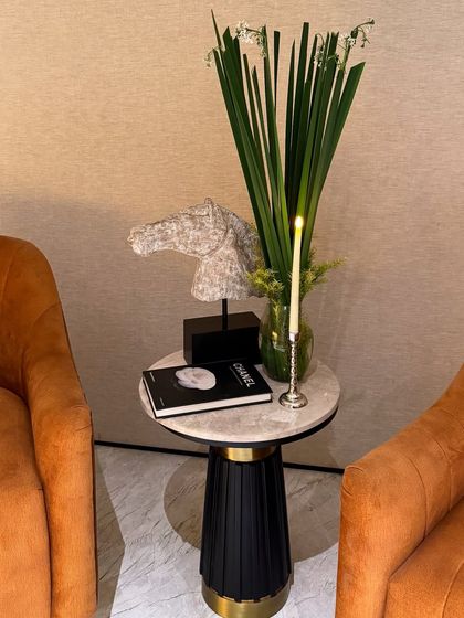 Even a small side table can be a moment of beauty. Here, a simple arrangement of green foliage and a single candle sit next to a horse head sculpture, blending our decor seamlessly with the client's personal style.