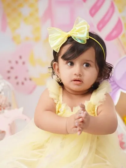A sweet close-up of the birthday girl in her yellow dress and bow, looking curious during her Candyland photoshoot.