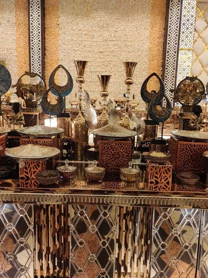 An intricately designed buffet counter featuring laser-cut patterns and a mix of copper and silver tones. The decorative elements and serveware create a rich, textured look for a special occasion.