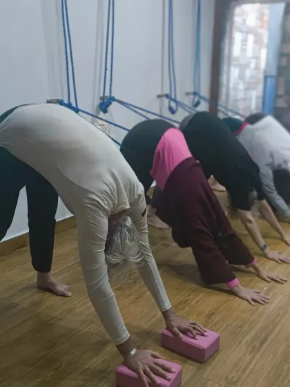 Life is a gift, and we live it to the fullest on our mats. A group of students finding joy and alignment in a supported downward dog pose.