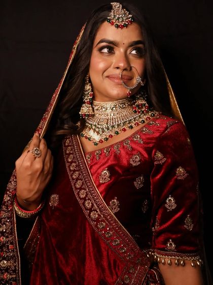 A side portrait that highlights the heavy embroidery on the velvet dupatta and the elegant bridal hairstyle.