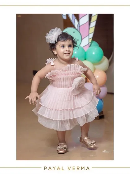 A truly special dress for a second birthday celebration. This blush pink organza dress features delicate pleating and a handcrafted floral detail, designed to make any little girl feel like the star of her party.