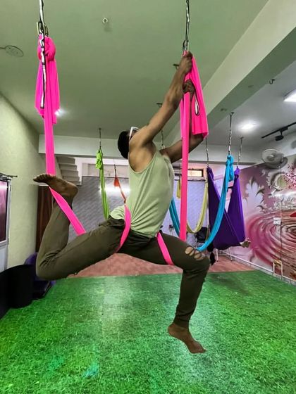 Stay fit, stay young. This student demonstrates a challenging aerial pose that requires significant upper body and core strength, proving that aerial yoga is for everyone.