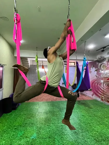 Stay fit, stay young. This student demonstrates a challenging aerial pose that requires significant upper body and core strength, proving that aerial yoga is for everyone.