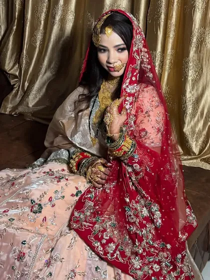 A Walima bride looking like a queen in her peach and red embroidered lehenga, with a soft and elegant makeup look.