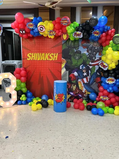 An action-packed Avengers superhero theme for a 3rd birthday. This setup includes a comic-style backdrop, character logos, and a vibrant red, blue, yellow, and black balloon garland.