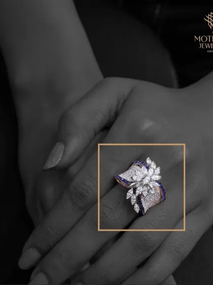 A creative black and white shot with a colour pop on a magnificent floral ring with blue and white diamonds, emphasizing its unique design.
