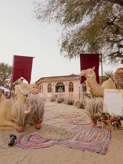 Life-sized camel figures and colorful rugs created a stunning entrance for the Banjara-themed Mehendi sundowner in the desert.