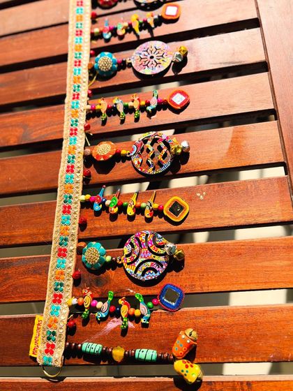 A vertical shot of the 'Rang-Tarang' toran, emphasizing the layers of beads, parrots, and mirrors.