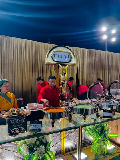 The Thai food counter in action, with chefs preparing plates for guests from large, steaming pots of curry.