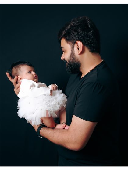 A father's gentle hold. This portrait highlights the special connection between a dad and his newborn daughter, capturing her delicate features and his loving gaze.