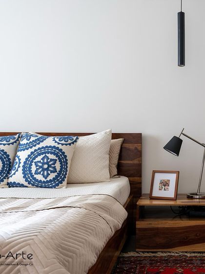 Dreamy comfort in every detail. A close-up of the bedside in the Minimalist Haven project, showing the harmony between the wooden furniture, modern lamp, and simple decor.