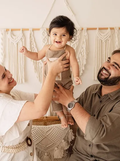 Parents playfully lift their giggling baby. This dynamic and happy image showcases the fun and energy of a family photoshoot.