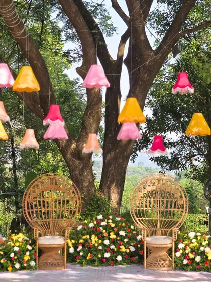 The seating area for the couple, framed by a large tree decorated with colorful lampshades. The design is whimsical, artistic, and perfect for a creative couple.