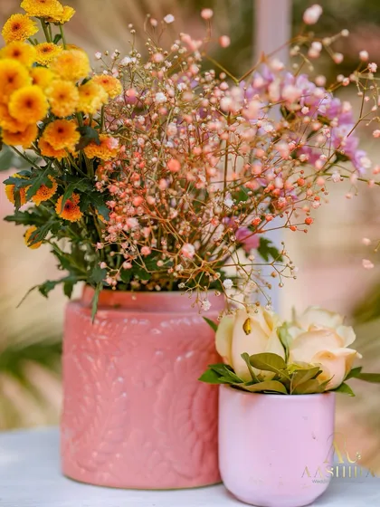 A pair of pink ceramic vases holding delicate arrangements of baby's breath and peach roses.