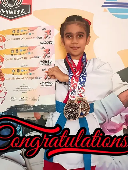The rewards of dedication. Pahal holds her certificates of competition and bronze medals, representing her outstanding performance against international competitors.