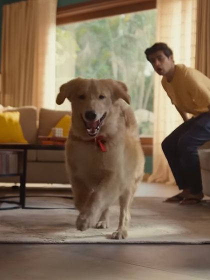 This shot captures a moment of casual interaction at home. The styling for the brother in a simple yellow t-shirt and jeans contrasts with the uniformed sister, highlighting their different paths while keeping the family setting relatable.