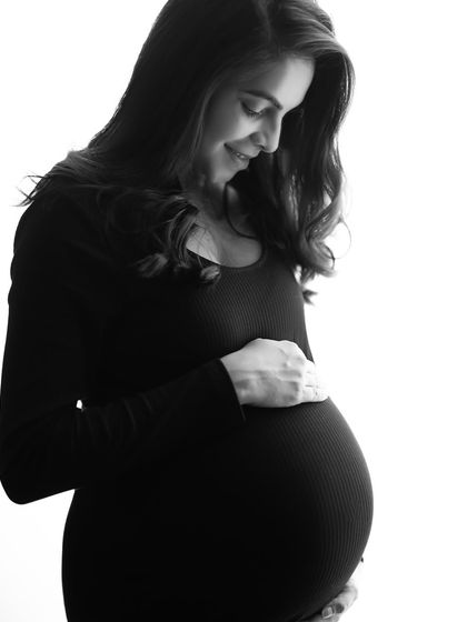 A beautiful black and white version of a classic maternity pose. The soft light highlights her gentle smile and the perfect curve of her belly.