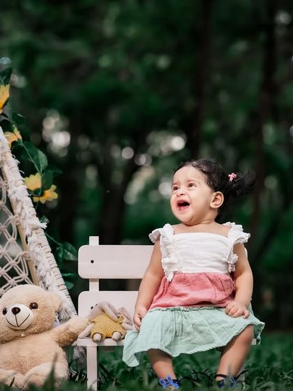 A candid moment of pure joy during an outdoor first birthday shoot. The natural background adds a beautiful, soft touch.