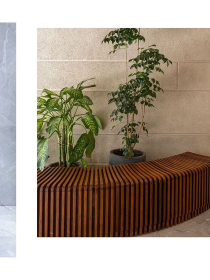 This image juxtaposes the cool, smooth surface of a marble wall with the warm, organic lines of a curved, slatted wooden bench, showcasing a sophisticated interplay of materials.