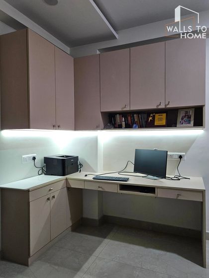 A minimalist and highly functional L-shaped home office setup. We designed this with ample overhead and base storage, an open shelf for books, and under-cabinet lighting for a well-lit workspace.