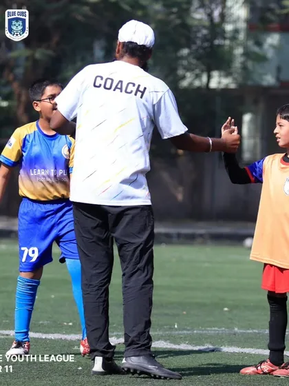 A coach gives a high-five to a young player during a U11 Thane Youth League match, a moment of encouragement.