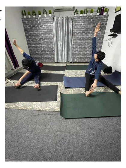 Students in a seated side stretch, Parivrtta Janu Sirsasana. This pose opens up the side body and hamstrings, and we work on deepening it with every breath.