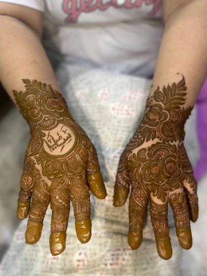 Both hands together, showing the beautiful contrast between the personalized name design and the full floral pattern.