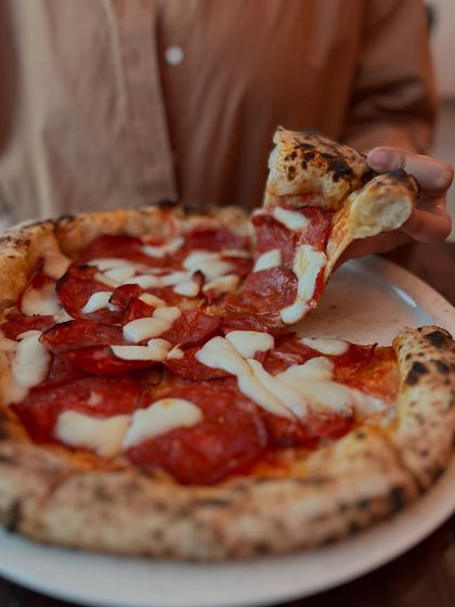 Diving into a classic pepperoni pizza, one perfect slice at a time.