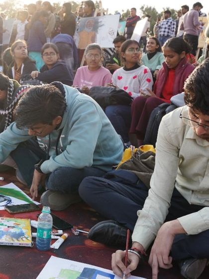 Young artists working diligently on the ground, surrounded by art supplies. Our events are open to all our students, providing them with real-world experience.