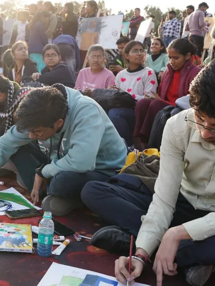 Young artists working diligently on the ground, surrounded by art supplies. Our events are open to all our students, providing them with real-world experience.