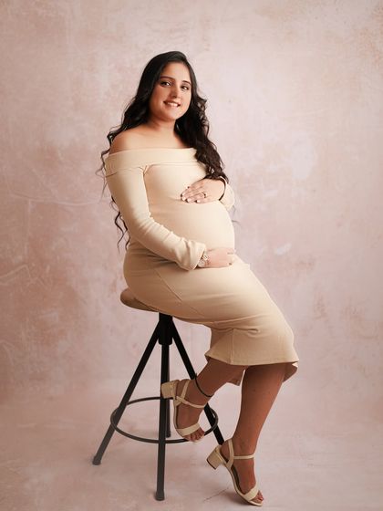An adorable mom-to-be in a simple, fitted cream dress. This studio portrait is sweet and elegant, showing that you can be glamorous in a minimal way.