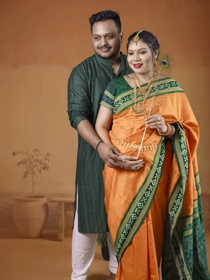 A classic portrait of the couple in their traditional outfits. The simplicity of the pose and the warm, earthy backdrop highlight their connection and cultural pride.