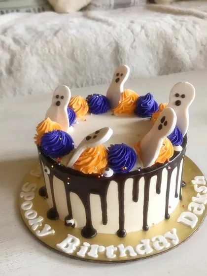 A spooky birthday cake with a chocolate drip and fondant ghosts, perfect for a Halloween-themed celebration.