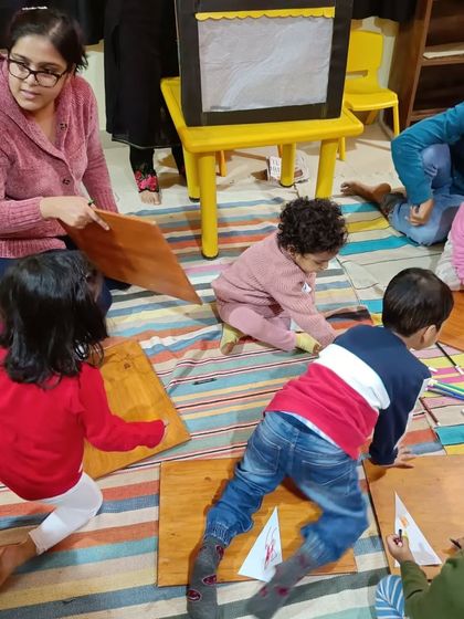 A storyteller helps the children with their craft, ensuring everyone can participate and feel successful.