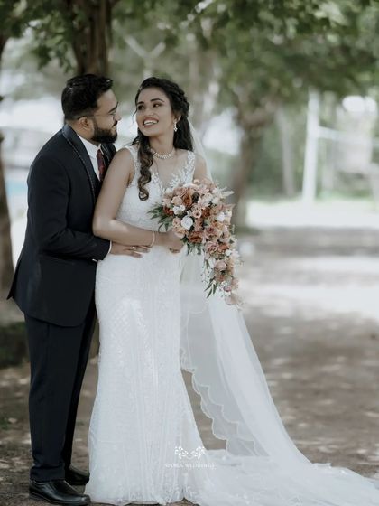 A classic portrait of the bride and groom, their happiness evident as they embrace in a beautiful garden setting.