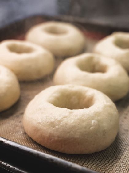 Steaming hot bagels just after being boiled, ready for their seed topping and final bake.